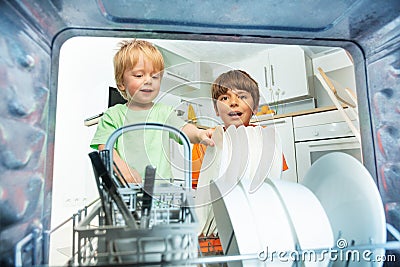 Two boys take dishes from dishwasher at kitchen Stock Photo