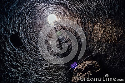 View from inside vertical tube downcast shaft with ladder. Stock Photo