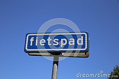 View on isolated dutch sign against blue sky with word fietspad english: cycling track Stock Photo