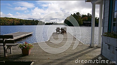 View of the lake from the boat deck of the cottage. Across the water is a cottage nestled among green trees Stock Photo