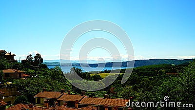 View of Lake Bracciano from a height with plants and trees and roofs with tiles in the foreground Stock Photo