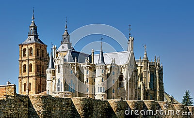 View of landmark cathedral of Astorga and historic Gaudi building behind ancient Roman surrounding wall. Stock Photo