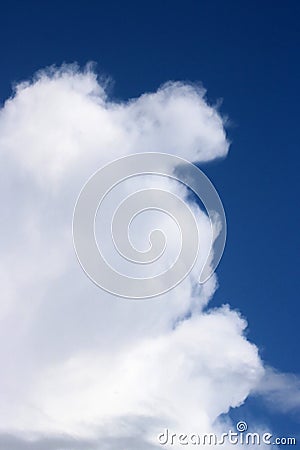 Fluffy white cloud resembling a face in blue sky Stock Photo