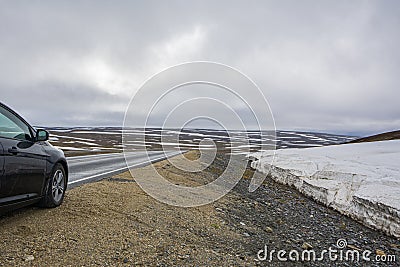 View of the layer of snow on the side and highland road with black car Stock Photo