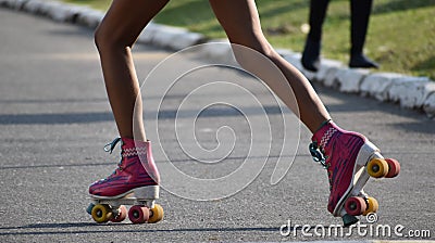 Legs of a young skater, who recreates himself by riding his four-wheeled skates on the asphalt in a sunset. Editorial Stock Photo