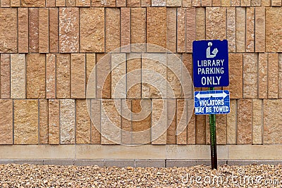 View of a library parking sign in front of an modern limestone wall with rough texture bricks Stock Photo
