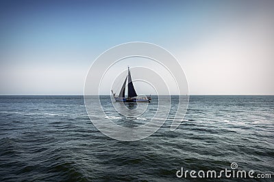 View of a lonely sailing ship with black sail, sailing on the turbulent barges of a Dutch lake Stock Photo