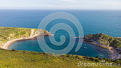 A view of the Lulworth Cove along the Jurrassic Coast in Dorset under a majestic blue sky and some white clouds Stock Photo