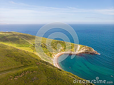 A view of the Lulworth Cove along the Jurrassic Coast in Dorset under a majestic blue sky and some white clouds Stock Photo