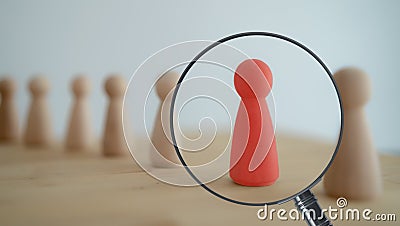 The view through the magnifier on the one wooden red person between other people. Resource management, recruitment, hire, headhunt Stock Photo
