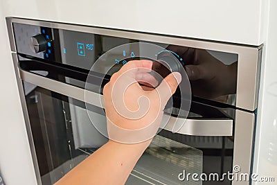 View of a male hand changing the oven temperature Stock Photo