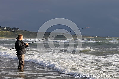View of man fishing from beach at Harlech, Wales Stock Photo