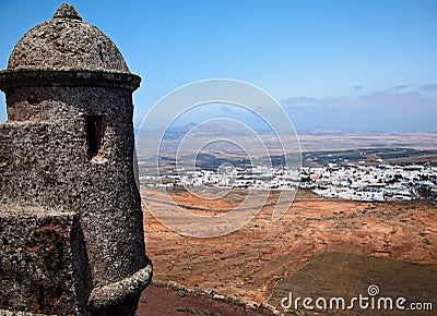 View from mediaeval fortress wall on hilltop. Village with white houses in the valley. Mountains and volcanoes on blue horizon Stock Photo