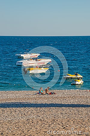 View of Mediterranean seacoast lonely beach with two women having sunbath and modern boats at Antalya historical downtown at Editorial Stock Photo