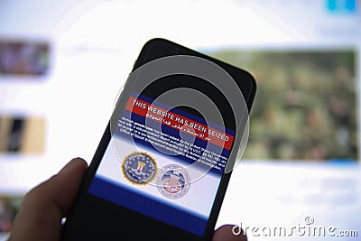 View on mobile phone screen with FBI notification this website has been seized, blurred arabic site flag background Editorial Stock Photo