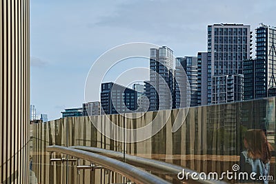 View of modern apartment buildings through glass pane with reflections on sunny day in london and girl walking past Stock Photo