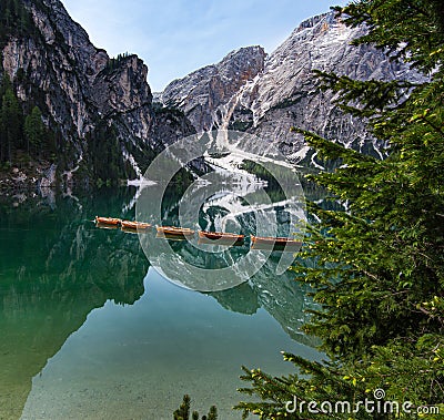 View of Mount Seekofel and boats in the evening light, mirroring in the clear calm water of iconic mountain lake Pragser Wildsee Stock Photo