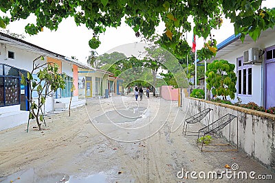 View of narrow street in a poor local village on Maldives, Dhangethi Island. White sand and grey walls Editorial Stock Photo