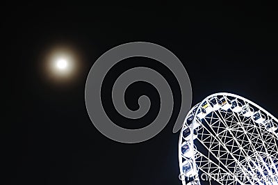 Night Sky with the Moon and a Quadrant of a Ferries Wheel Stock Photo