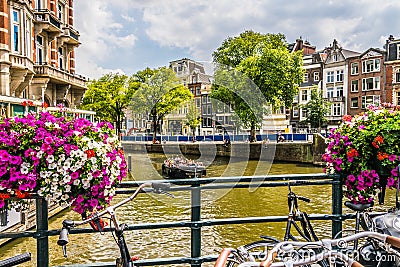 View of one of the canals in Amsterdam. Very flowery bridge and many tourists in the streets on a summer afternoon Editorial Stock Photo