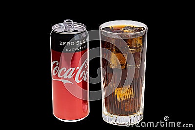 View of open coca can and soda with ice in crystal glass isolated on black background. Drink concept. Editorial Stock Photo