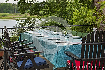 View of outdoor party table covered with sea green table cloth ready served. Beautiful nature around. Stock Photo