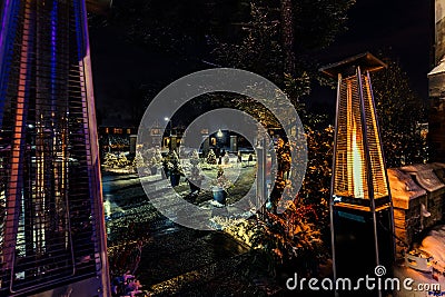 View of outdoor propane heater turned on against backyard background decorated with various lights at winter time Stock Photo