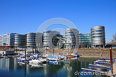 View over marina on modern silver office buildings five boats against blue sky Editorial Stock Photo