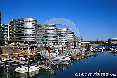 View over marina on modern silver office buildings five boats against blue sky Editorial Stock Photo