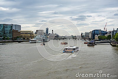 Lots of boats on River Thames London, HMS Belfast on left and a river cruise boat center frame Editorial Stock Photo