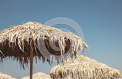 View over vintage straw sun umbrellas against blue sky. Stock Photo
