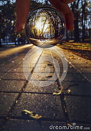 View of the Park alley with walkers and tourists through a glass ball at sunset in Stavropol, Russia Stock Photo