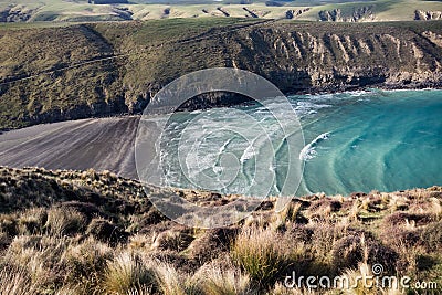 View on periodic waves in rocky Tumbledown bay with black sand beach on Banks Peninsula Stock Photo