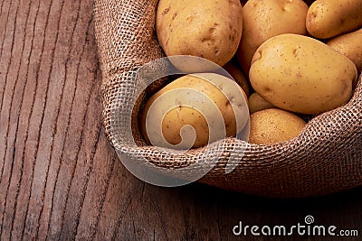 View of pile of new potatoes with jute bag on wooden desk Stock Photo