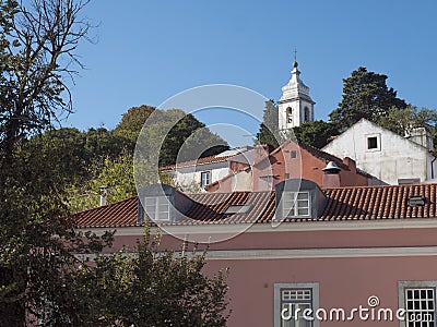 View of pink house and church bell tower at Alfama at Santa Maria Maior district, Lisbon, Portugal. Blue sky background Stock Photo