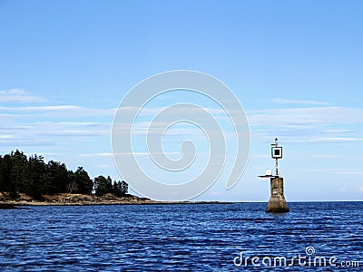 View of a port hand day beacon marking a reef hidden by the ocean at high tide. Stock Photo