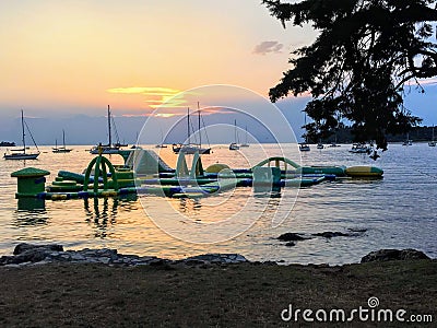 A view of a pretty water playground floating on the ocean during sundown surrounded by boats outside of Rovinj, Croatia. Stock Photo