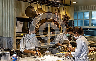 View of professional women`s doing bakery on the kitchen white table in the open kitchen of the bakery in souffle and me cafe Editorial Stock Photo