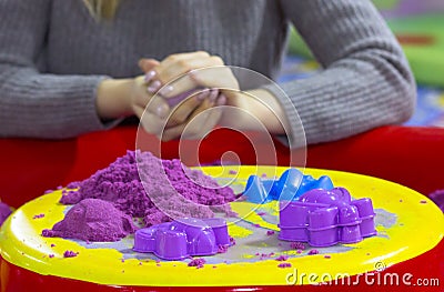 View of purple kinetic sand and forms for modeling on the woman hands molding ball background Stock Photo