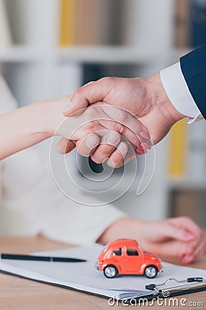 View of realtor shaking hands with customer near house model in office Stock Photo