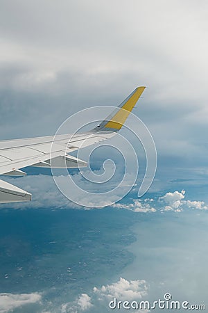 View of right wing from window of airplane flying up in the sky, through clouds in atmosphere. Plane in flight. Up in the air. Stock Photo