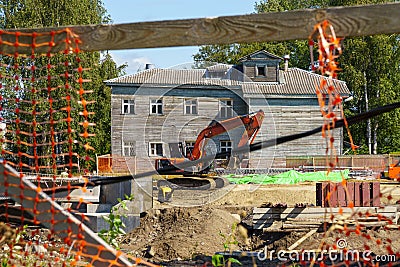 View of construction site in city with digger through a hole in fence Stock Photo