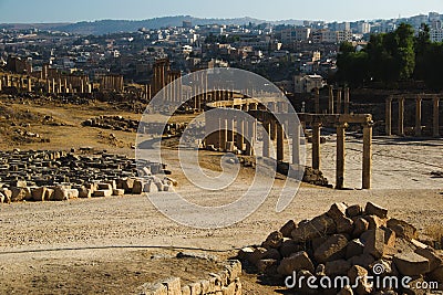 View ruins Oval Forum and long colonnaded street or cardo ancient Greco-Roman city Gerasa. Modern Jerash on background. Tourism in Stock Photo