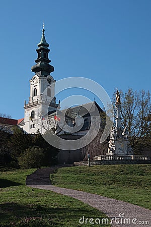 View of Saint Emmeram Basilica main tower surrounded by Nitra castle, with plague column with Immaculate statue on top. Stock Photo