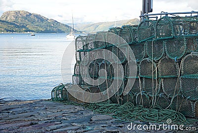 View of the sea beyond weathered prawn traps piled on a dock in western Scotland Stock Photo