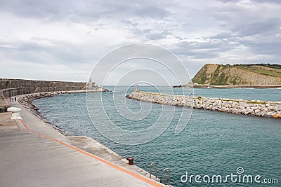 View of the sea and coast with lighthouse. Biscayne bay with scenic coastline. Basque country landscape. Breakwater stones. Stock Photo