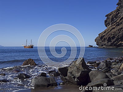 View on sea horizon with old Sailing ship from black sand beach Playa De Masca Stock Photo