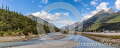 View of shallow Skagway River and Skagway airport in Alaska. Blue cloudy sky and mountain peaks in the background Stock Photo