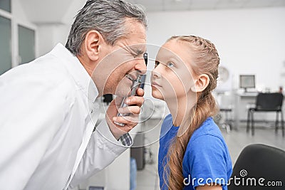 Oculist looking through special tool at eye pupil in clinic Stock Photo