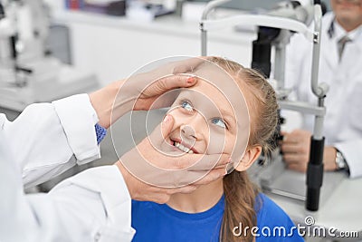 View from side of female oculist checking eye pupil of girl Stock Photo